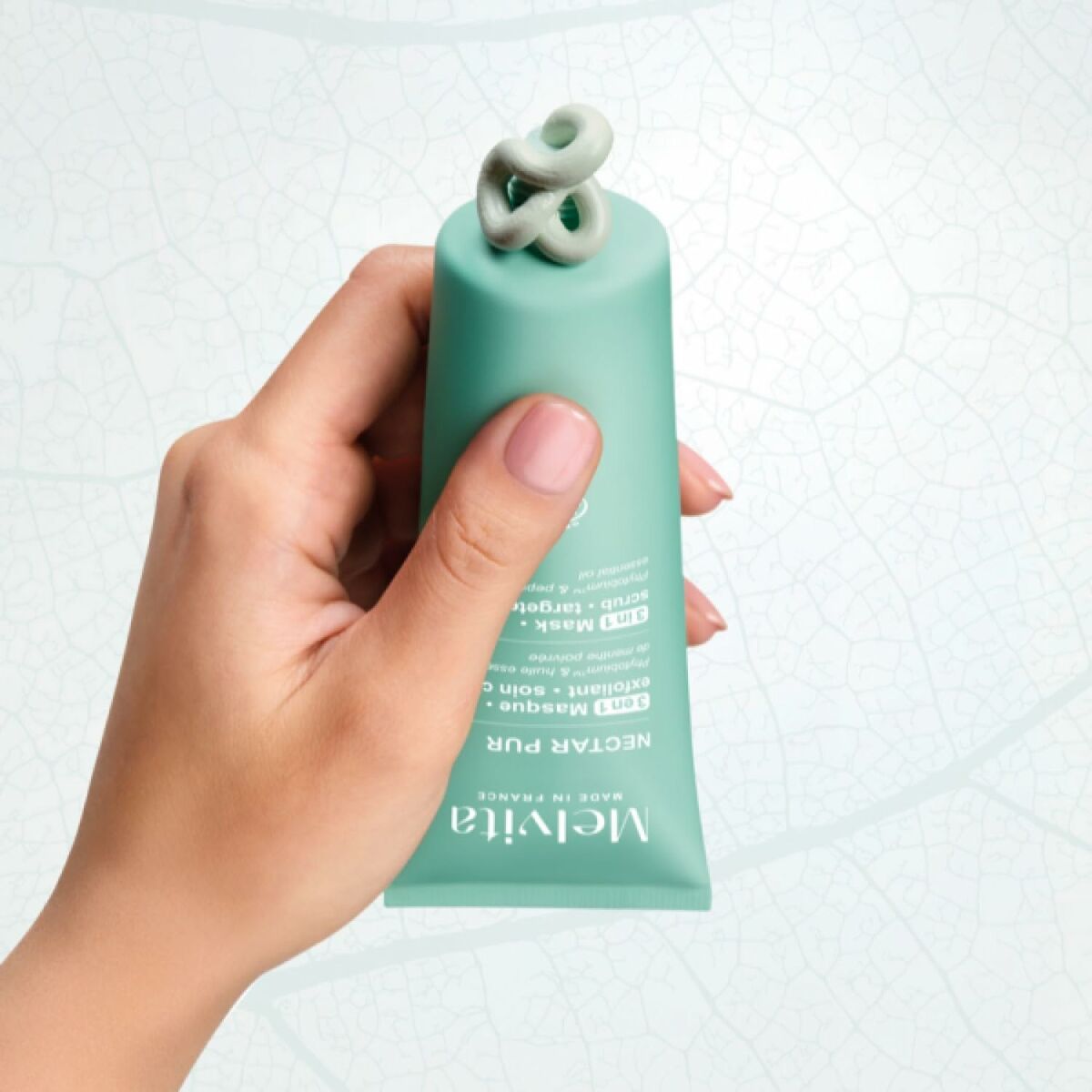 Main hand holding Melvita NECTAR PUR gel nettoyant visage, showcasing the product packaging for cleansing skincare.