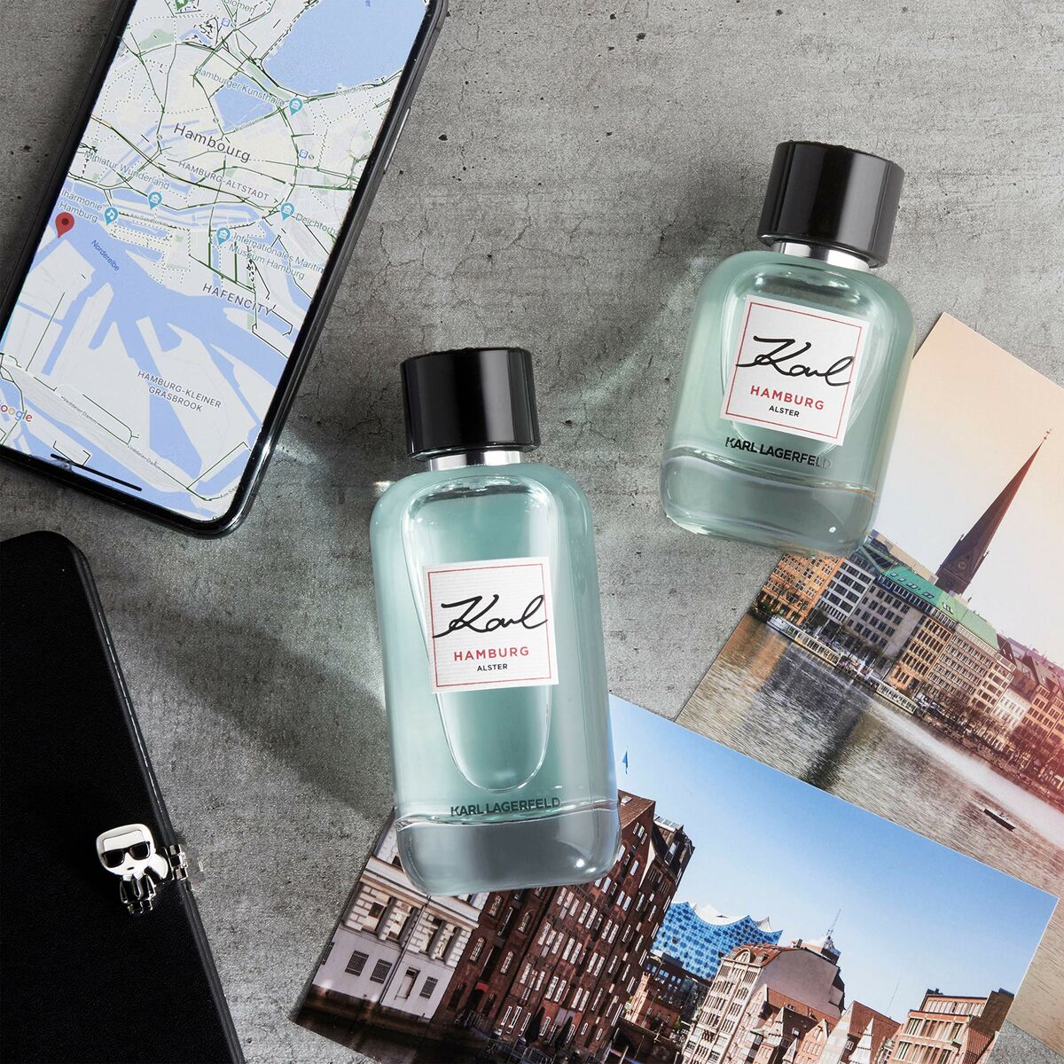 Bottles of Karl Lagerfeld Karl Hamburg Alster 60ml on a table with a smartphone and travel photos.