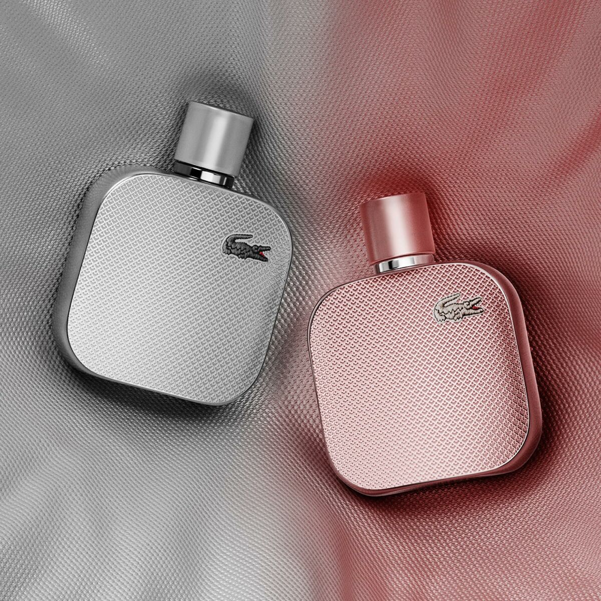 Lacoste L.12.12 POUR ELLE perfume bottles in gray and pink against a textured background.