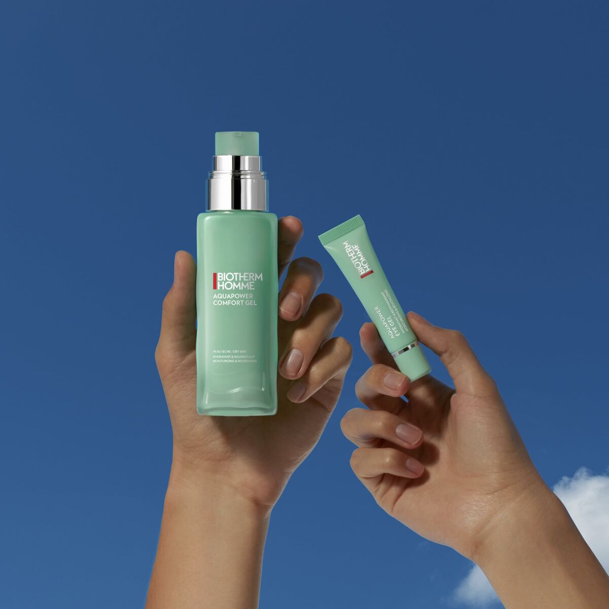Biotherm Homme Aquapower Cream and Comfort Gel for men, showcasing skincare products in hands against a blue sky.