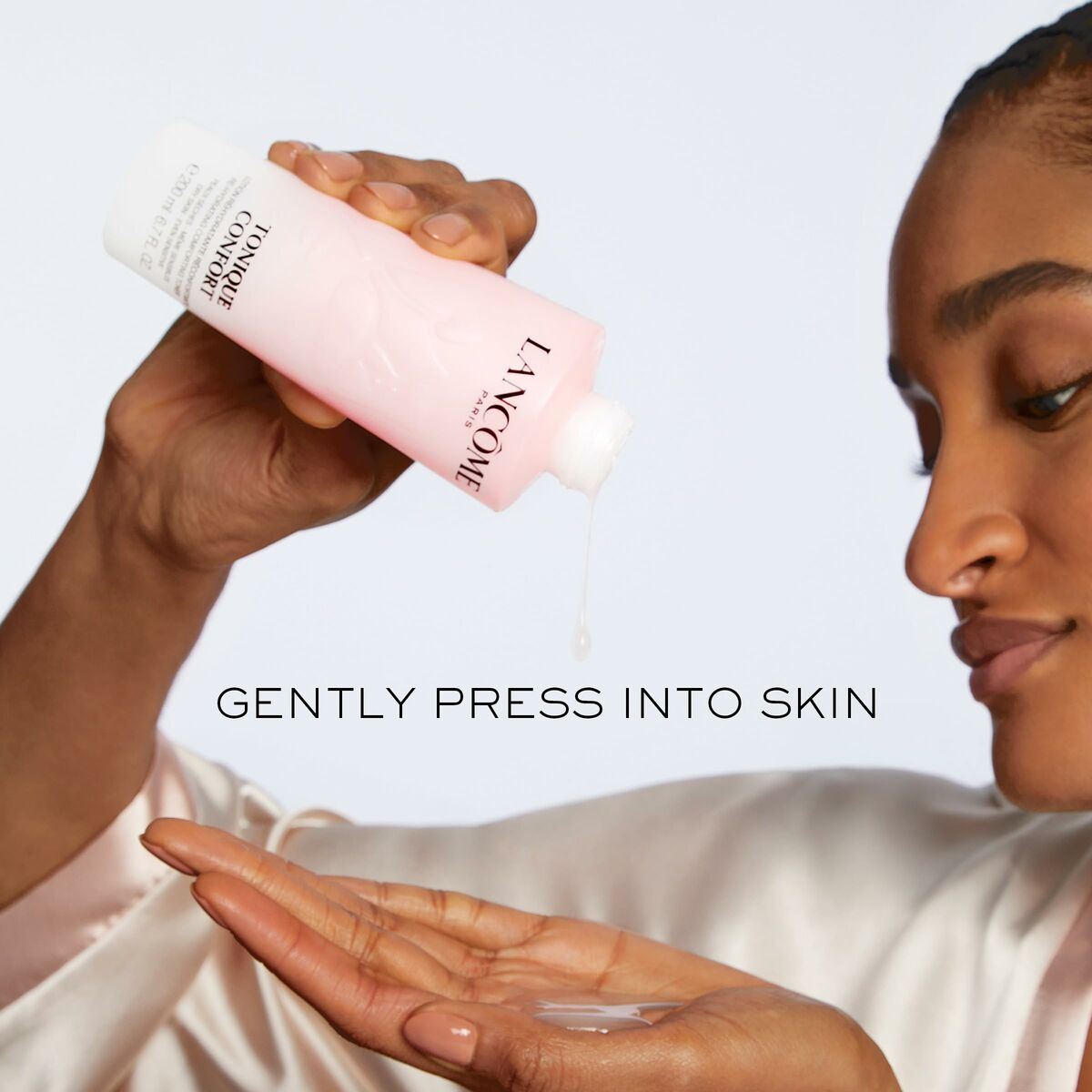 Woman applying Lancôme Confort Gel Cleanser to her hand, promoting gentle skincare for dry skin.