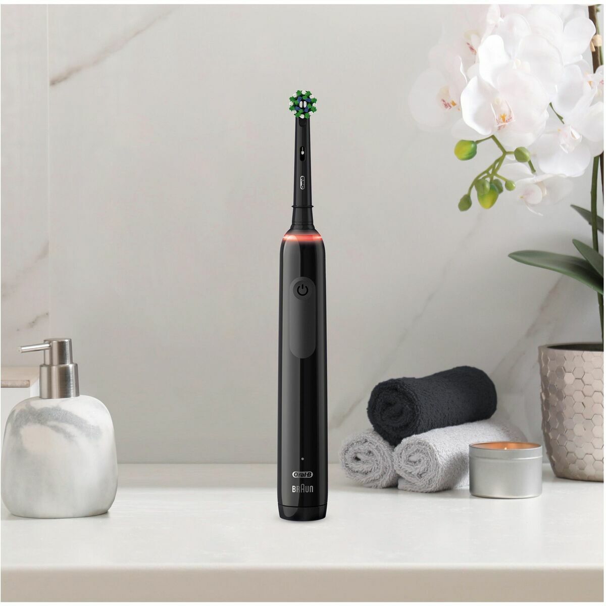 Brosse à dents électrique Braun Noir sur un comptoir de salle de bain avec des serviettes et des accessoires.