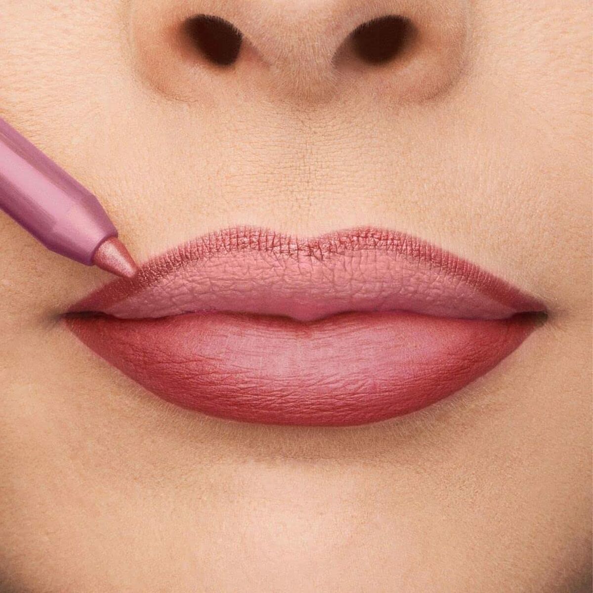 Close-up of lips being lined with a mauve lip pencil for a perfect finish in a beauty routine.