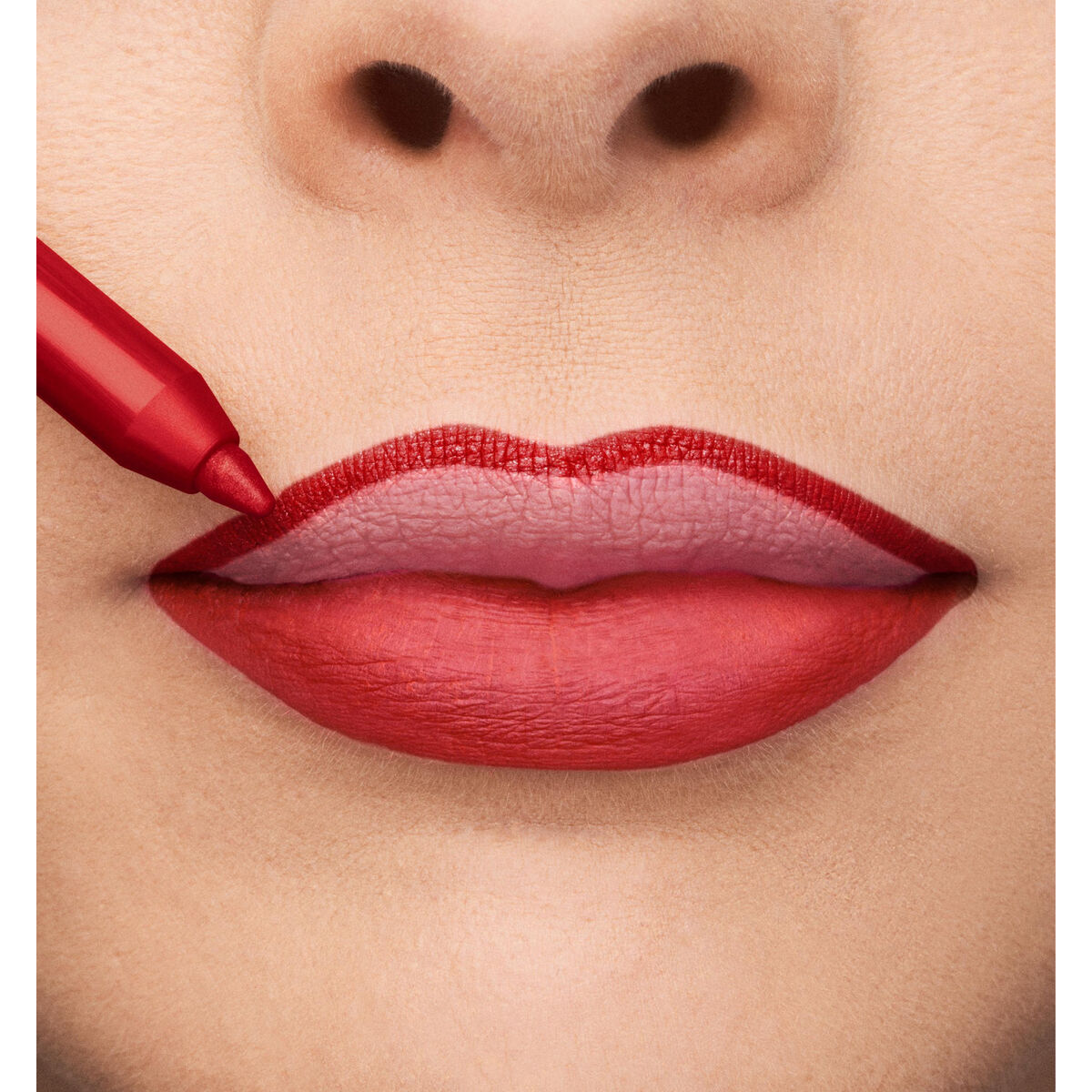 Close-up of bold red lips being outlined with a lip liner, showcasing a vibrant lip color look.