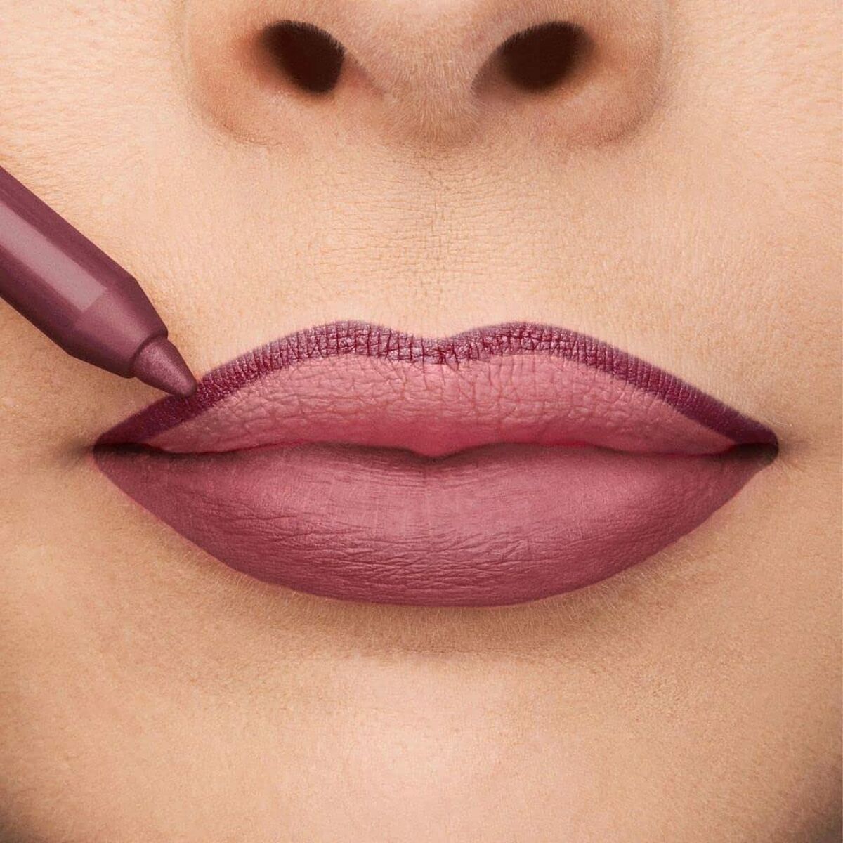 Close-up of lips being lined with a deep pink lip marker, showcasing defined edges and a luscious matte finish.